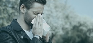 A boy is covering his mouth while sneezing